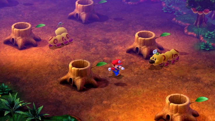 Mario running through a level of tree stumps, a caterpillar is to the right
